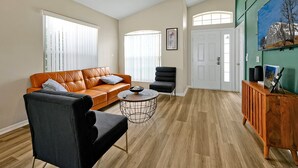 A living room with a sofa, armchair, coffee table, and a cabinet. - Family & Pet-Friendly Pool Home | Near Disney (Davenport)