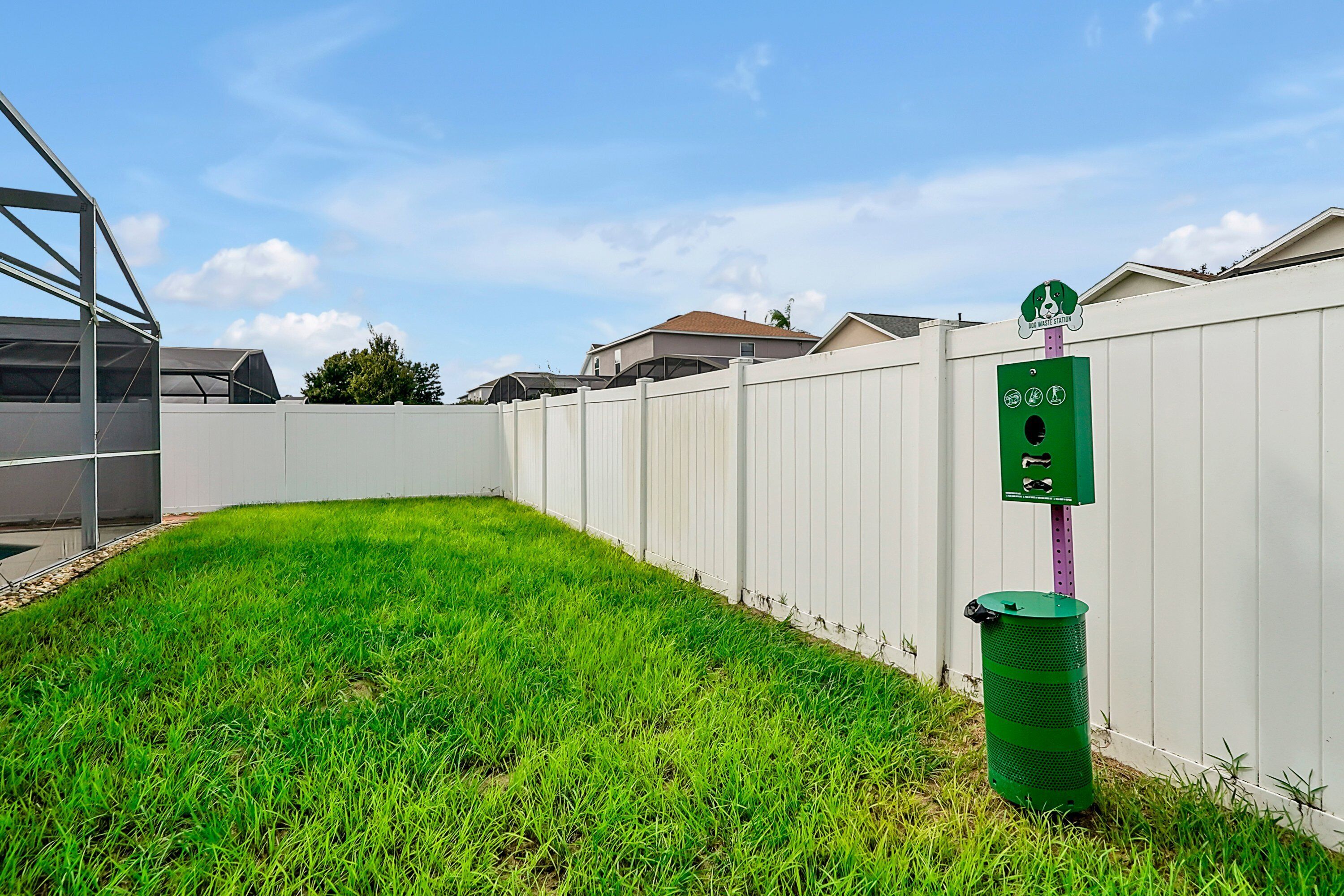 A fenced backyard with a green trash bin and a recycling bin.