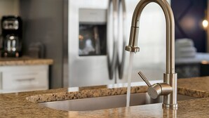 A kitchen with a stainless steel faucet, granite countertop, and a refrigerator in the background. - Family & Pet-Friendly Pool Home | Near Disney (Davenport)
