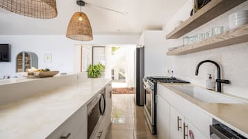 A modern kitchen with a central island, built-in appliances, and wooden shelves.