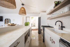 Een moderne keuken met een centraal eiland, ingebouwde apparatuur en houten planken.