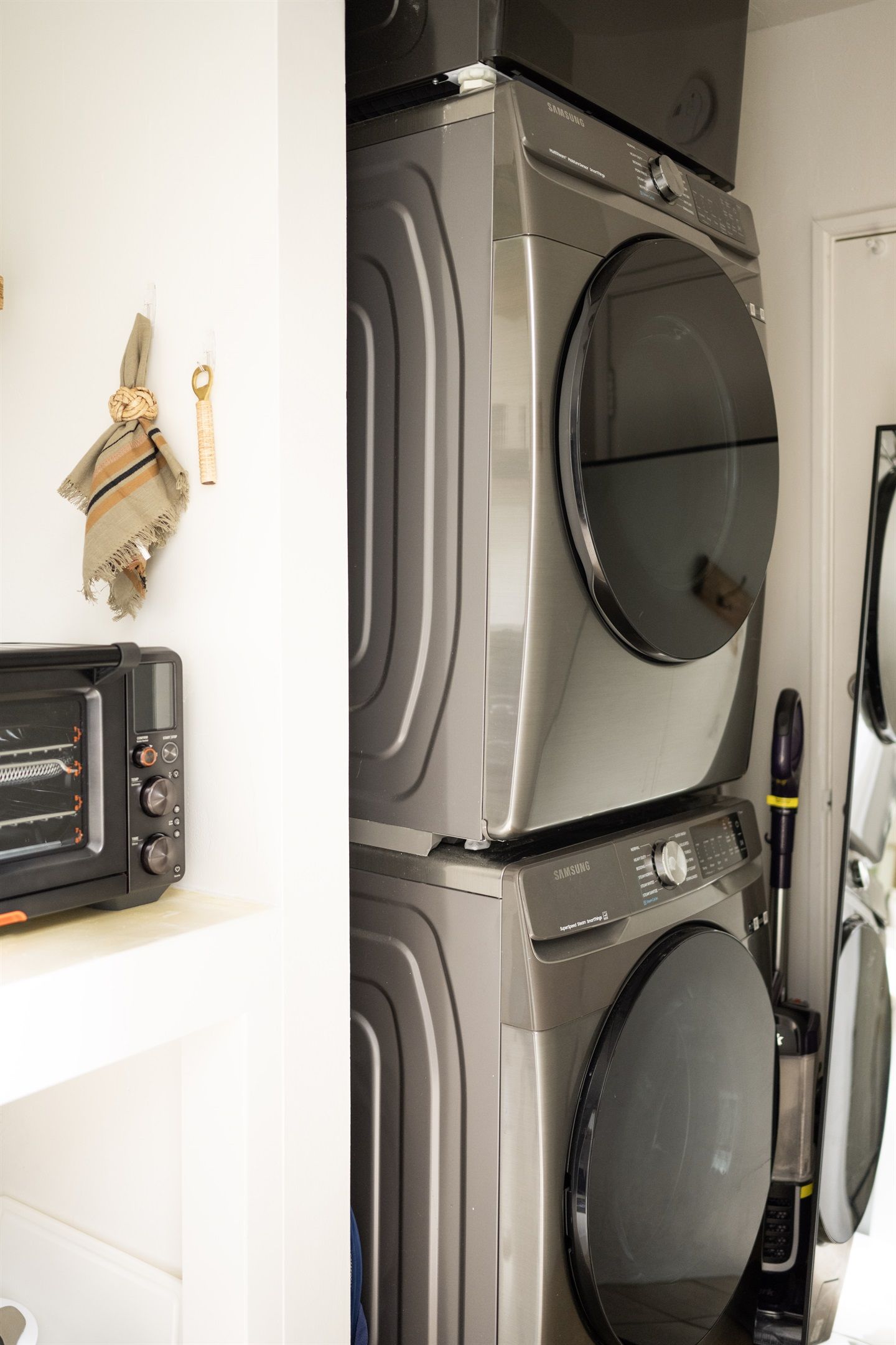 A laundry area with stacked washers and dryers, a microwave, and a toaster oven.