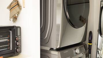 A laundry area with stacked washers and dryers, a microwave, and a toaster oven.