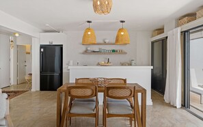 Een moderne keuken met een zwarte koelkast, een wit aanrechtblad en twee hangende pendelverlichting.