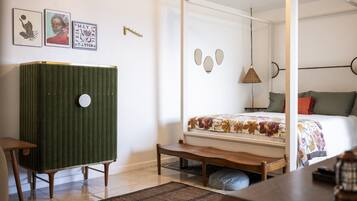 A bedroom with a four-poster bed, a green chest of drawers, a wooden bench, and a hanging lamp.
