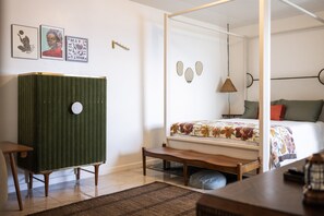Un dormitorio con cama con dosel, un aparador verde, un banco de madera y una lámpara colgante.