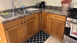 A kitchen with wooden cabinets, a stainless steel sink, a coffee maker, and a stove.