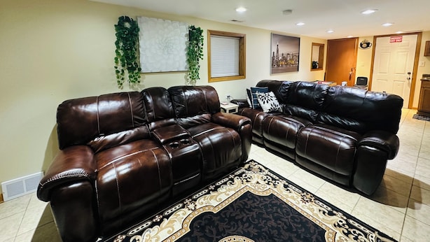 A living room with two brown leather sofas, a patterned rug, and a cityscape wall art.