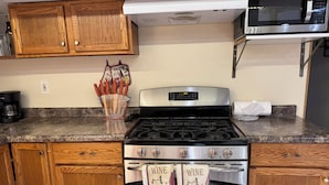 A kitchen with wooden cabinets, a stainless steel stove, and a microwave above.