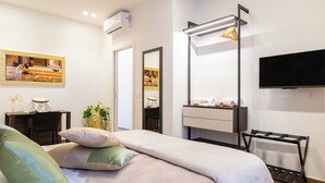 Una habitación de hotel moderna con cama, escritorio, silla, televisor y espejo.