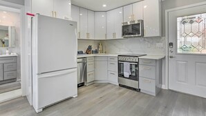 Eine moderne Küche mit weißen Schränken, einem eingebauten Backofen und einem Edelstahl-Kühlschrank.