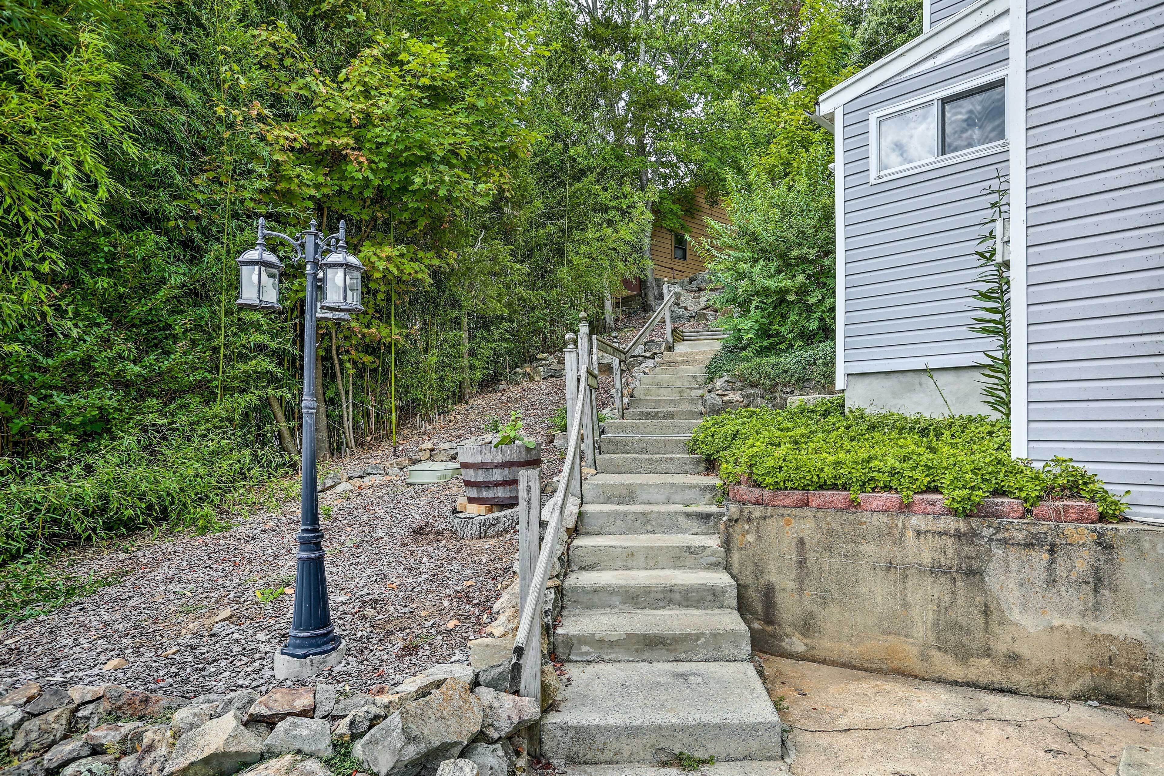 A staircase leading to a house with a stone railing, surrounded by greenery.