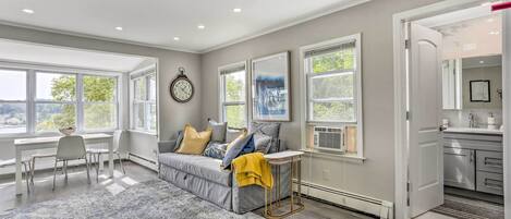 A modern living room with a grey sofa, a small table, and a large window.
