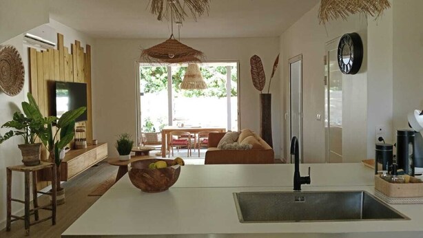 A modern kitchen with a central island, a dining area with a table and chairs, and a living room with a sofa. - Villa Lola in the heart of Baie Orientale, 100m from the beach. 800l tank (Saint martin)