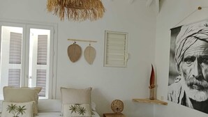 A bedroom with a bed, pillows, a hanging basket, a wall-mounted shelf, and a large framed picture. - Villa Lola in the heart of Baie Orientale, 100m from the beach. 800l tank (Saint martin)
