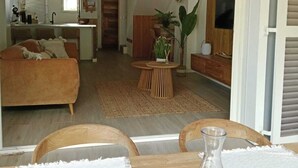 A modern living room with a sofa, a dining table with chairs, a hanging woven light fixture, and a television. - Villa Lola in the heart of Baie Orientale, 100m from the beach. 800l tank (Saint martin)