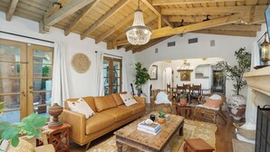 A cozy living room with a wooden ceiling, a chandelier, a sofa, a coffee table, and various decorative items. - Casa Gitana: Moroccan-Infused Spanish Retreat with Pool and Casita (Palm Springs)