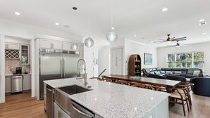 A modern kitchen with a central island, stainless steel appliances, and a dining area with a wooden table and chairs. - 221 Cordillo at S Forest Beach, New Build, Easy to Beach, Private Pool (Hilton Head Island)