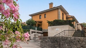 A two-story building with a stone wall in the foreground and a staircase leading to the entrance. - House Llanes (Poo) near the beach - Traudel (Llanes)