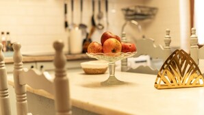 Una encimera de cocina con un expositor de vidrio que contiene manzanas, una silla de madera y una estantería decorativa de metal.