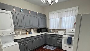 A kitchen with grey cabinets, a white refrigerator, a microwave, and a stove.