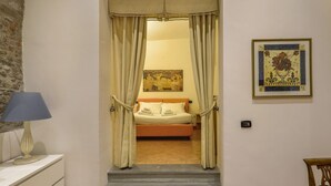 A bedroom with a bed, curtains, a painting, and a lamp. - Lietta Apartment in Florence (Firenze)