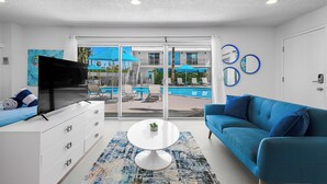 A modern hotel room with a TV, sofa, and a view of an outdoor pool area. - South Palm Springs Studio - Unit 101 Float Apartments (Palm Springs)