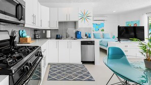 A modern kitchen with white cabinets, a black stove, and a dishwasher. - South Palm Springs Studio - Unit 101 Float Apartments (Palm Springs)