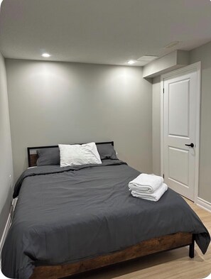 Ein Schlafzimmer mit Bett, Kissen, einer Tür und einer Deckenleuchte.