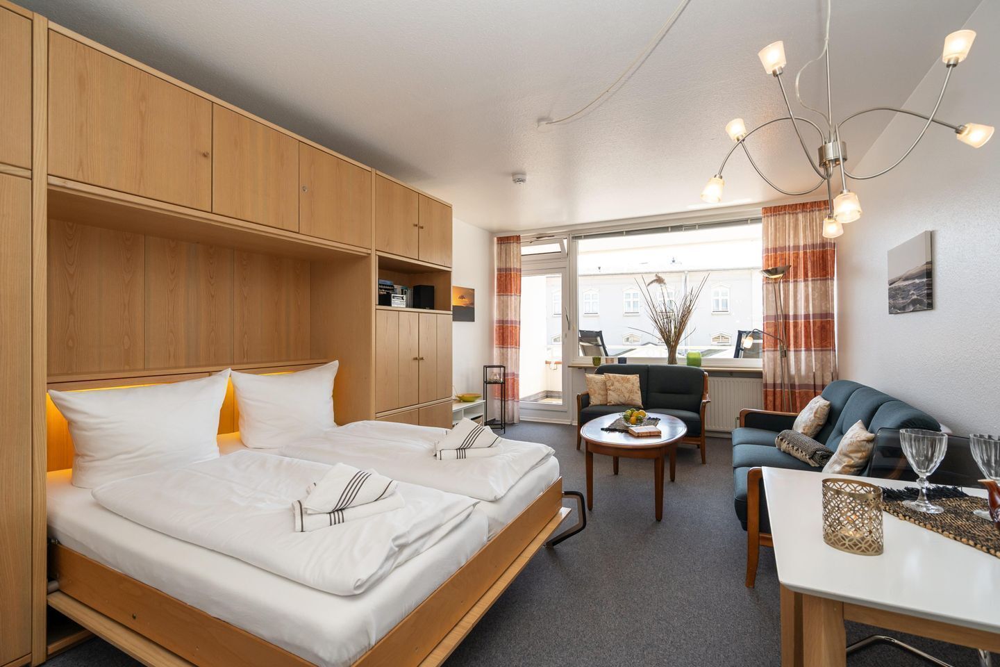 Ein modernes Hotelzimmer mit einem großen Bett, einer Couch, einem Esstisch und Blick auf die Stadt.