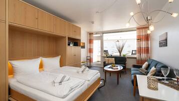 Ein modernes Hotelzimmer mit einem großen Bett, einer Couch, einem Esstisch und Blick auf die Stadt.