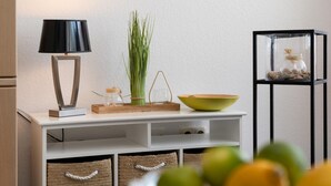A white console table with a black lamp, a green bowl, a glass jar, and a plant. - Strandstraße - Cozy, central 1-room apartment, close to the beach, balcony, (Westerland)