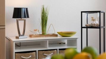 Een witte console tafel met een zwarte lamp, een groene kom, een glazen pot en een plant.