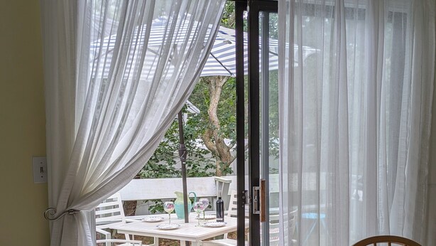 Ein Essbereich mit Tisch für zwei Personen, eine Schiebetür zu einer Terrasse und Blick auf diese.