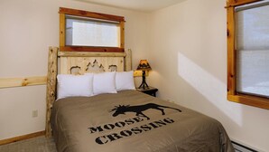 Ein Schlafzimmer mit Bett, Fenster, Lampe und einem Holz-Kopfteil.
