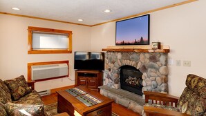 Ein gemütliches Wohnzimmer mit Kamin aus Stein, einem Flachbildfernseher und Möbeln mit Muster.