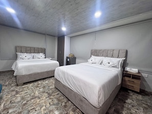 A hotel room with two beds, a wardrobe, a nightstand, and a small cabinet. - Hospedaje Casa Rueda (Barranquilla)