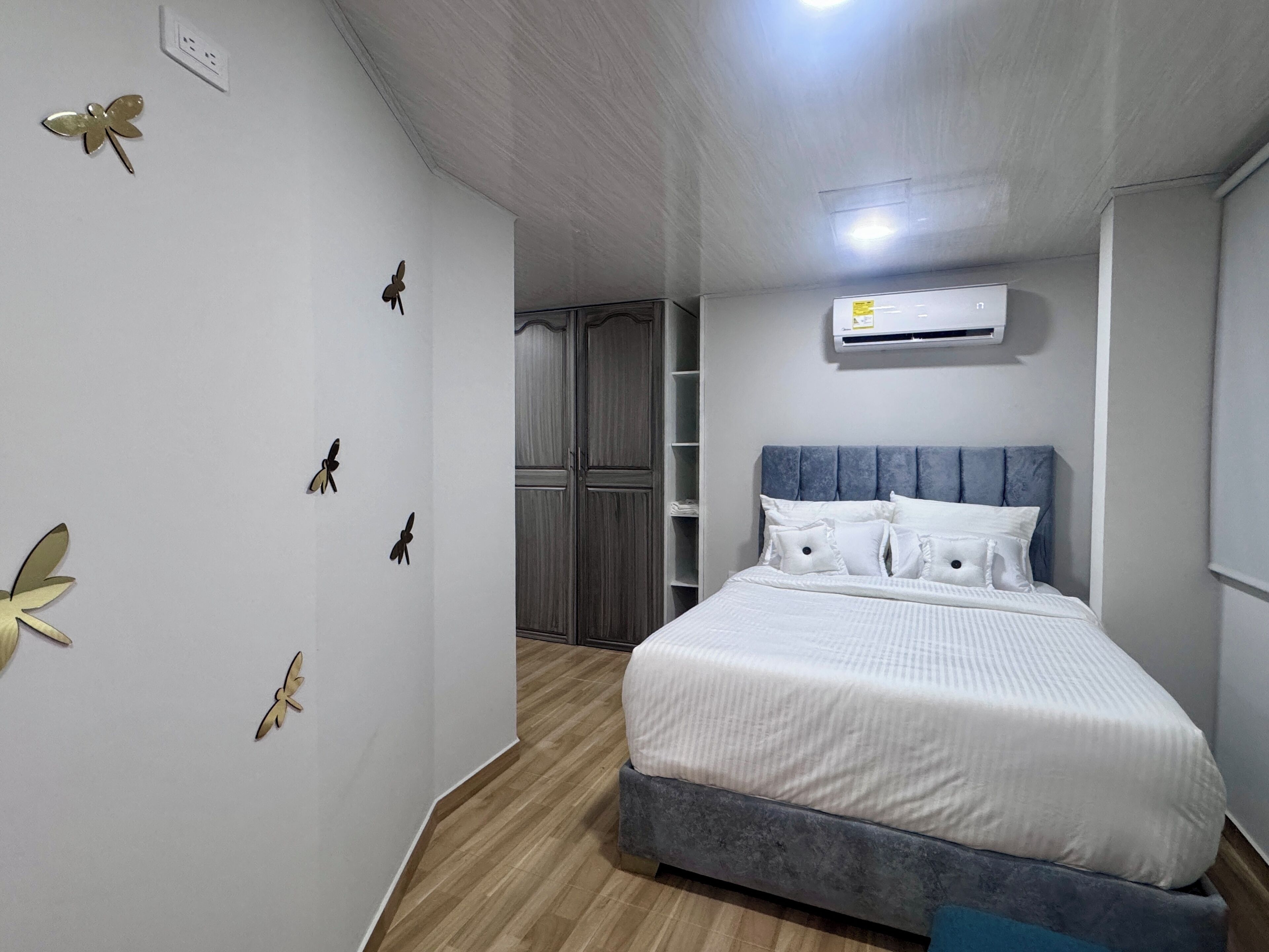 Un dormitorio con cama, armario y equipo de aire acondicionado.