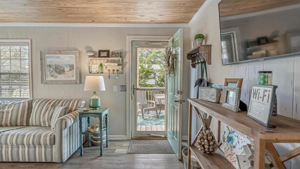 Un salon chaleureux avec un canapé à rayures, une petite table avec une lampe et une porte donnant sur un balcon.