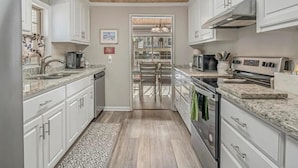 Une cuisine moderne avec des meubles blancs, un plafond en bois et une vue sur la salle à manger.