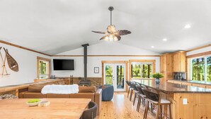 A spacious living area with a wooden dining table, sofas, and a TV mounted on the wall. - River Retreat w/ hot tub, beach & arcade/ game room (Packwood)