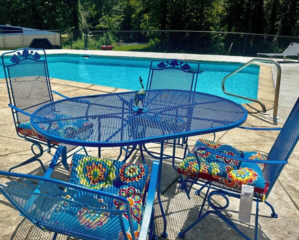 A blue metal outdoor pool area with a round table and chairs, surrounded by a metal fence. - Creek Home with Waterfalls
(Leesburg)