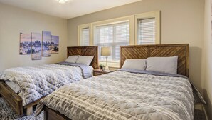 Un dormitorio con dos camas, ventilador de techo y ventana con persianas.