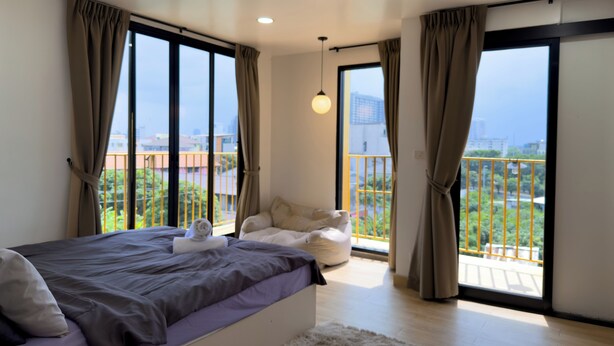 Un dormitorio moderno con una cama grande, vistas a un balcón y un paisaje urbano.