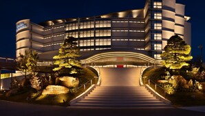 Un hotel moderno con facciata curva, diversi piani e un ingresso centrale con una scala.