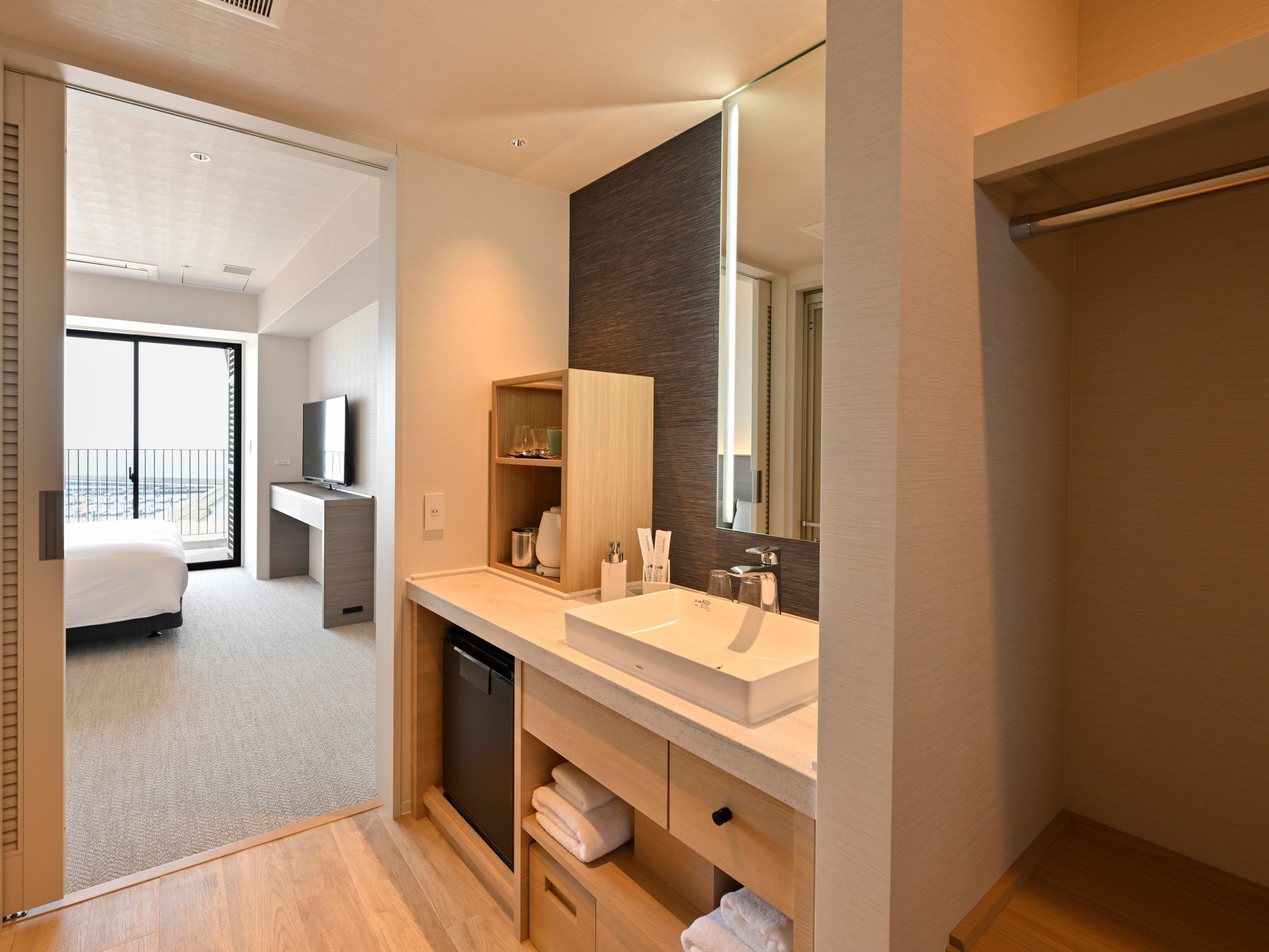 A modern hotel bathroom with a large mirror, a sink, and a shower area.