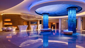 Una moderna hall con una fontana circolare, zone relax e un design di soffitto originale.