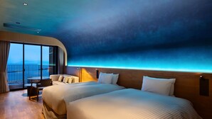 Una camera d'hotel moderna con due letti, un balcone vista mare e pavimento in legno.