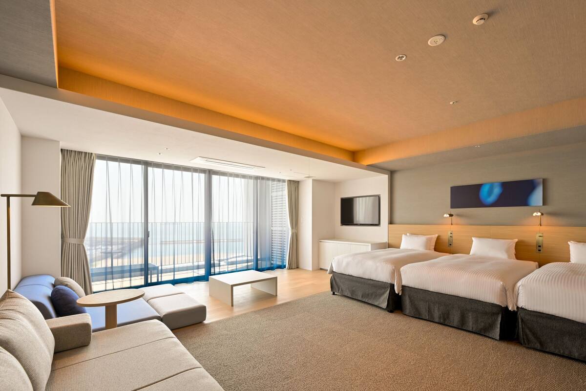 Una moderna camera d'albergo con un letto grande, un divano, un tavolino e una TV.