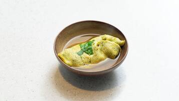 A bowl of food with a green garnish on a speckled surface.